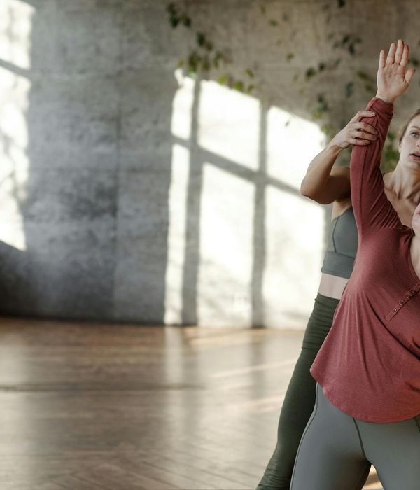 Person stretching gently in a bright, sunlit room, symbolizing well-being.