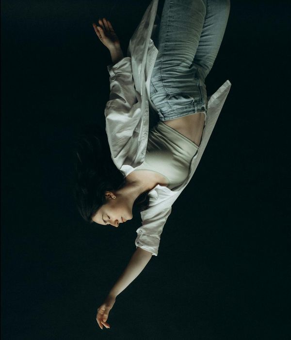 Woman in a calm, balanced pose against a dark, minimalist background.